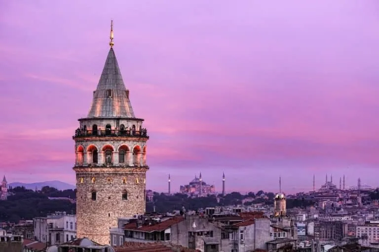 Purple-hued Galata Tower against evening sky, iconic medieval stone monument.