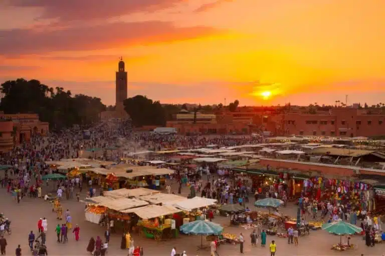 Colorful stalls in a Marrakech public bazaar, showcasing traditional Moroccan textiles, spices, and ceramics under vibrant market canopies.