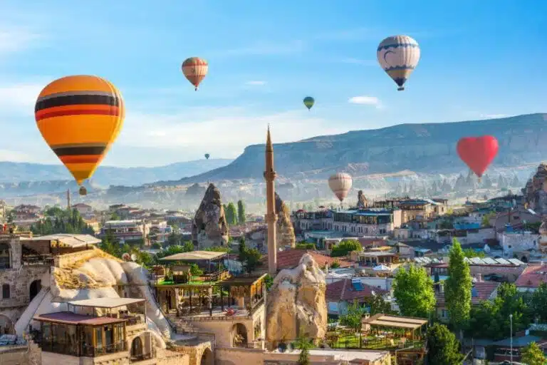 Hot air balloon floating over a mosque in Goreme at sunrise, showcasing Cappadocia's stunning landscape.